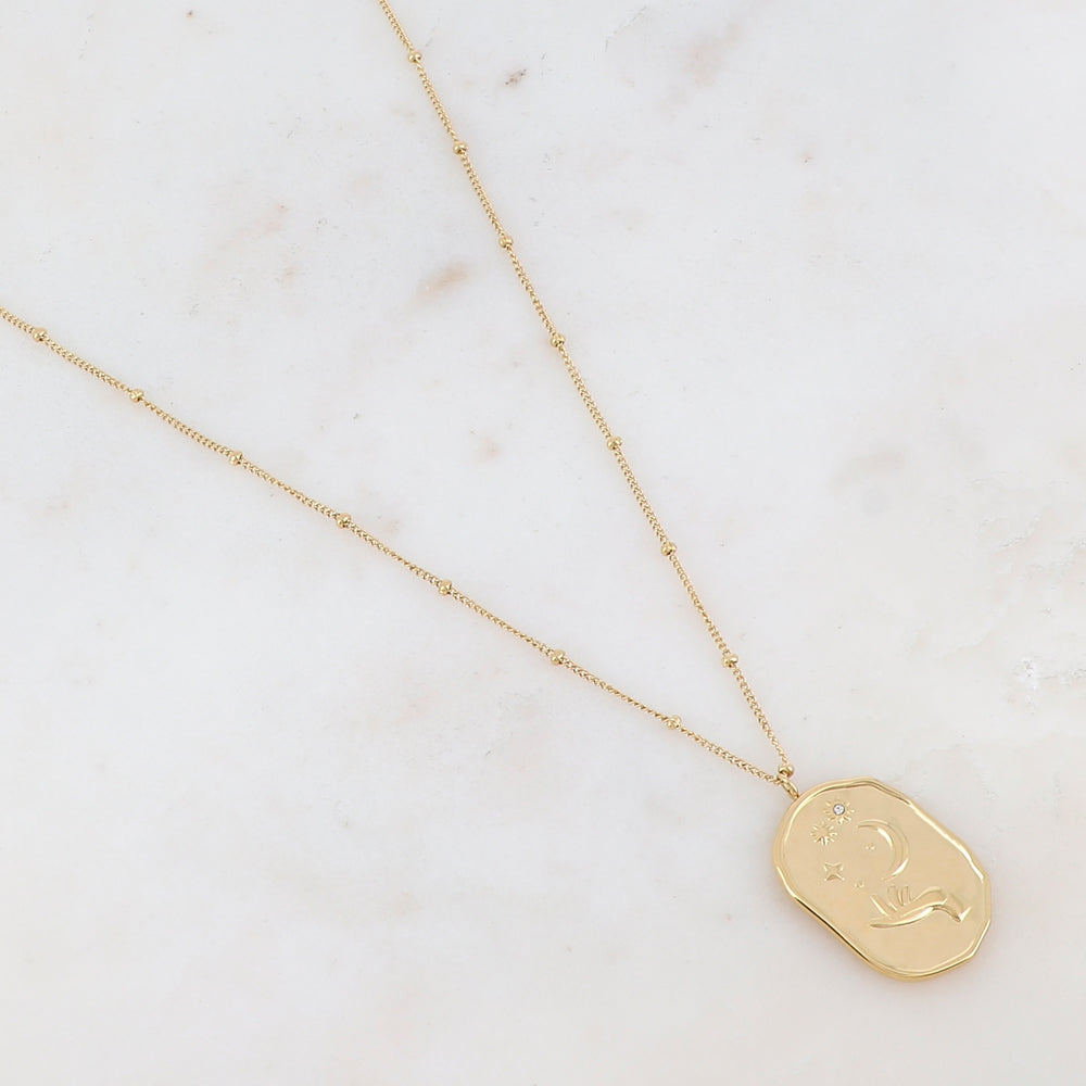 Collier doré composé d'un pendentif en forme géométrique avec différents motifs : main, soleil, lune et étoile, et d'un strass blanc 40+5 cm