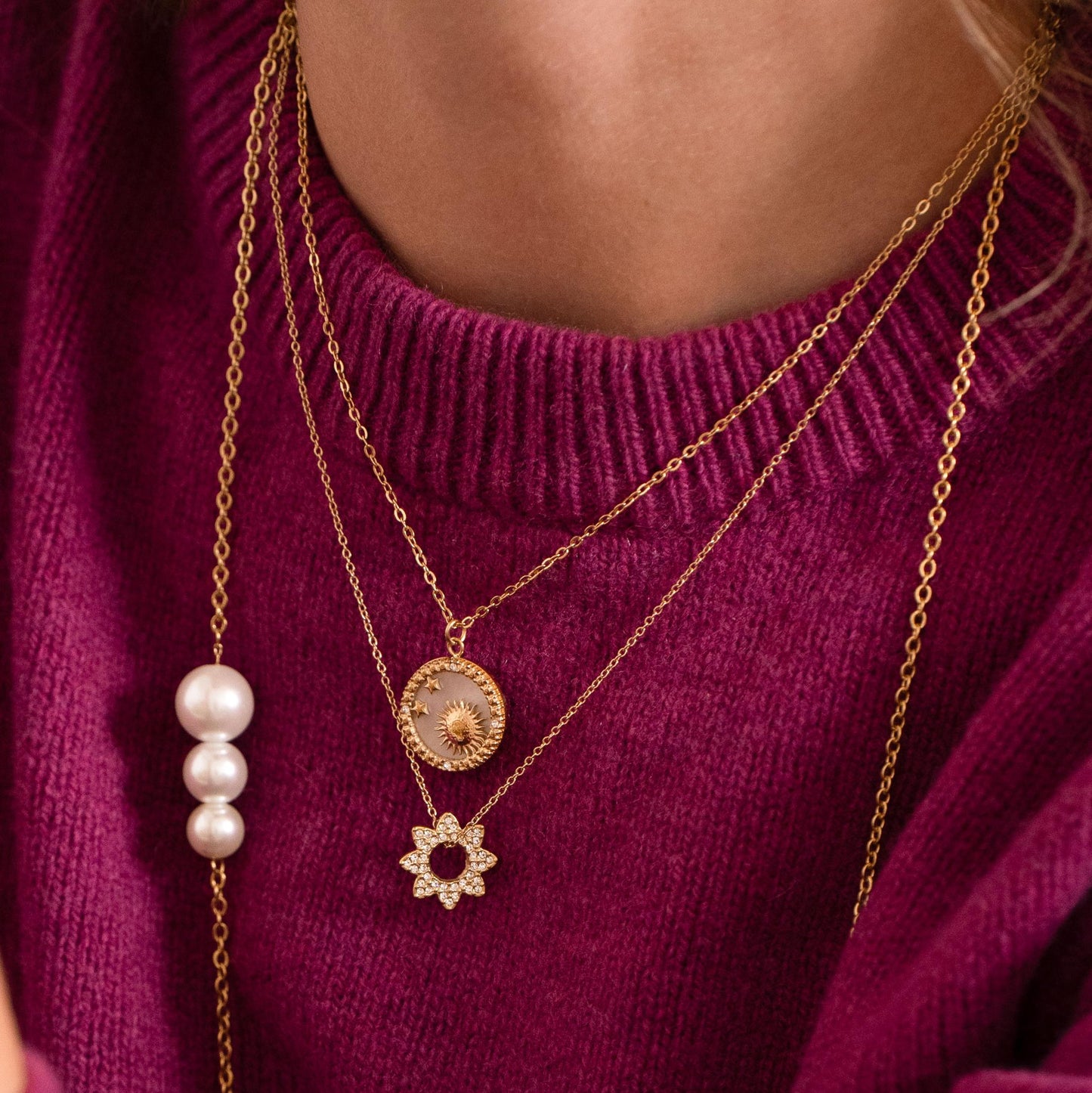 Collier doré composé d'un pendentif rond avec un fond nacré et orné d'étoiles, d'un soleil et de strass blancs 40+5 cm
