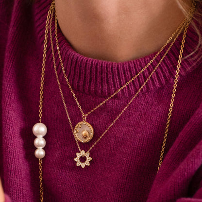 Collier doré composé d'un pendentif rond avec un fond nacré et orné d'étoiles, d'un soleil et de strass blancs 40+5 cm