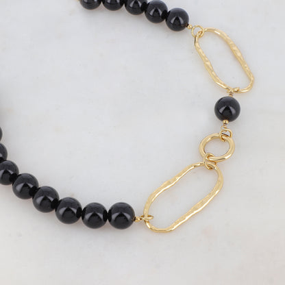 Collier doré composé de 2 anneaux ovales martelés, d'1 anneau rond lisse et de pierres onyx 42+7 cm