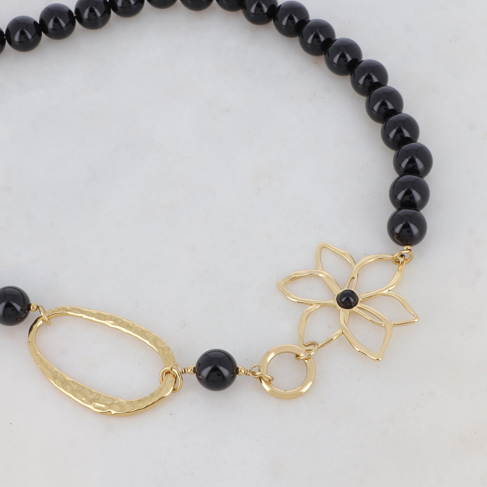 Collier doré composé d'un anneau ovale martelé, d'un anneau rond lisse, d'une fleur et de pierres onyx 42+7 cm