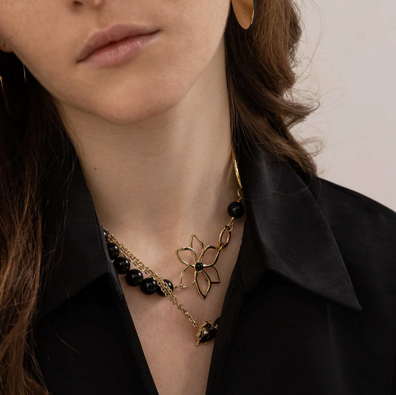 Collier doré composé d'un anneau ovale martelé, d'un anneau rond lisse, d'une fleur et de pierres onyx 42+7 cm