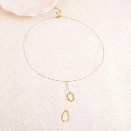 Collier doré avec un strass et deux anneaux texturés au bout de chaînes tombantes 50+5 cm