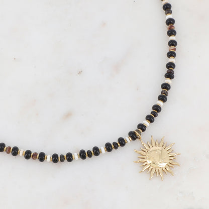 Collier doré composé de perles en pierre naturelle noires et blanches et pendentif forme soleil 39+7 cm