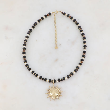 Collier doré composé de perles en pierre naturelle noires et blanches et pendentif forme soleil 39+7 cm