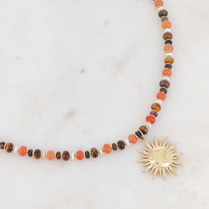 Collier doré composé de perles en pierre noire, blanche, agate orange et oeil de tigre et pendentif forme soleil 39+7 cm