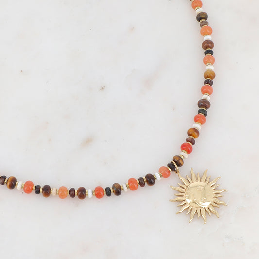 Collier doré composé de perles en pierre noire, blanche, agate orange et oeil de tigre et pendentif forme soleil 39+7 cm