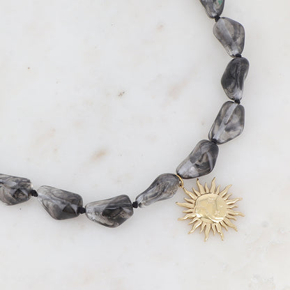 Collier doré avec perles en résine translucide gris et pendentif forme soleil 39-41 cm