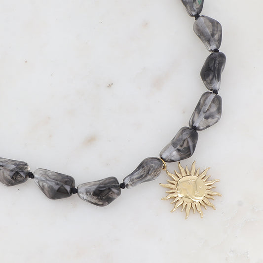 Collier doré avec perles en résine translucide gris et pendentif forme soleil 39-41 cm