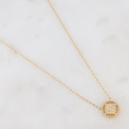Collier doré avec un pendentif rond ajouré de façon géométrique et orné de 4 strass blancs 38+7 cm